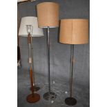 A mid 20th century vintage teak standard lamp and three others all in cream and beige lampshades.