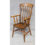 An antique elm seated slat back Windsor armchair on turned stretchered supports. H.109cm