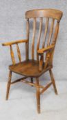 An antique elm seated slat back Windsor armchair on turned stretchered supports. H.109cm