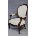 A 19th century carved mahogany framed open armchair on cabriole supports upholstered in ivory
