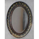 An early 20th century oval floral carved wall mirror with bevelled plate. 94x64cm