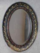 An early 20th century oval floral carved wall mirror with bevelled plate. 94x64cm