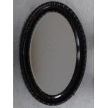 An early 20th century oval wall mirror with gadrooned frame and bevelled plate. 83x55cm