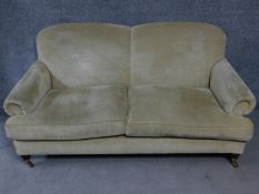 A Victorian style two seater settee on turned supports on brass cup casters. H.84 W.185 D.85cm