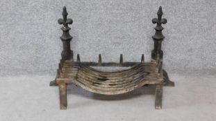 An antique cast iron set of fire dogs & basket with Fleur de Lys finials. H.57xW.85xD.34cm