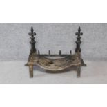 An antique cast iron set of fire dogs & basket with Fleur de Lys finials. H.57xW.85xD.34cm