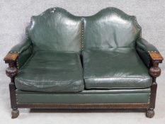 A mid 20th century carved oak frame leather upholstered two seater sofa on bulbous reeded