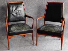 A pair of Danish 1970's vintage teak framed armchairs in deep green leather upholstery, retail label