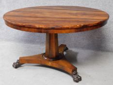 An early 19th century rosewood circular tilt top dining table on tripod pedestal base terminating on