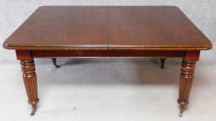 A Victorian style mahogany extending dining table on turned reeded tapering supports with three