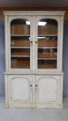 A 19th century painted bookcase/dresser with glazed doors enclosing shelves above panel doors. H.