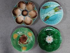 Four antique majolica plates. One designed by George Jones of pineapples in a basket, the waterlilly