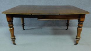 A Victorian mahogany extending table on turned tapering supports terminating on brass cup casters.