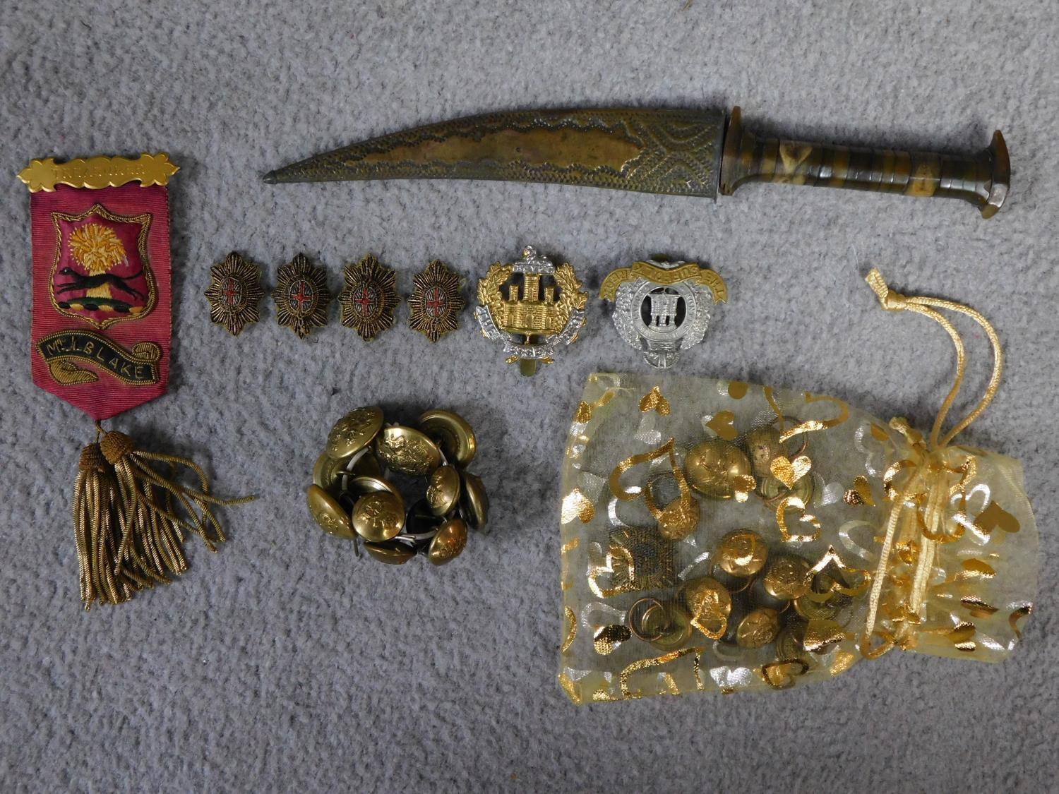 A collection of military regalia and brass buttons along with a bone handled dagger with hammered
