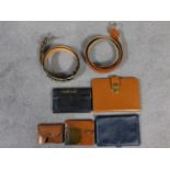 A collection of vintage leather travel and money wallets and two belts. One belt is ostrich and