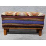 A kilim upholstered foot stool on square feet. H.42 L.75 W.27cm