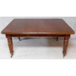 A Victorian style mahogany extending dining table on turned reeded tapering supports with three