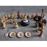 A collection of twenty one German Hummel hand painted figures and wooden display stand with