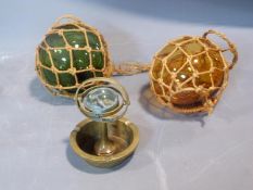 Two antique fishing floats and a brass ship's compass ashtray. H14cm.