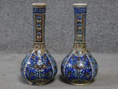 A pair of handpainted ceramic vases with a stylised floral and foliate design in blues, greens and