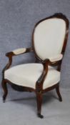 A 19th century carved mahogany framed open armchair on cabriole supports upholstered in ivory