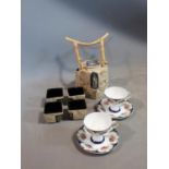 A ceramic Malaysian tea set and a pair of porcelain tea cups and saucers. The tea cups have a
