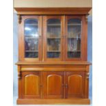 A Victorian style mahogany library bookcase with three arched glazed doors enclosing shelved