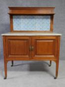 An Edwardian mahogany washstand with tiled back superstructure above marble top on panel doors on