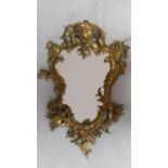 A Rococo style ormolu gilt brass mirror. Rocaille formed frame with wooden back. H.80xW.51cm