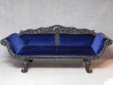 A 19th century Anglo Indian carved ebonised scroll end sofa with blue velvet upholstery on scroll