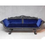 A 19th century Anglo Indian carved ebonised scroll end sofa with blue velvet upholstery on scroll