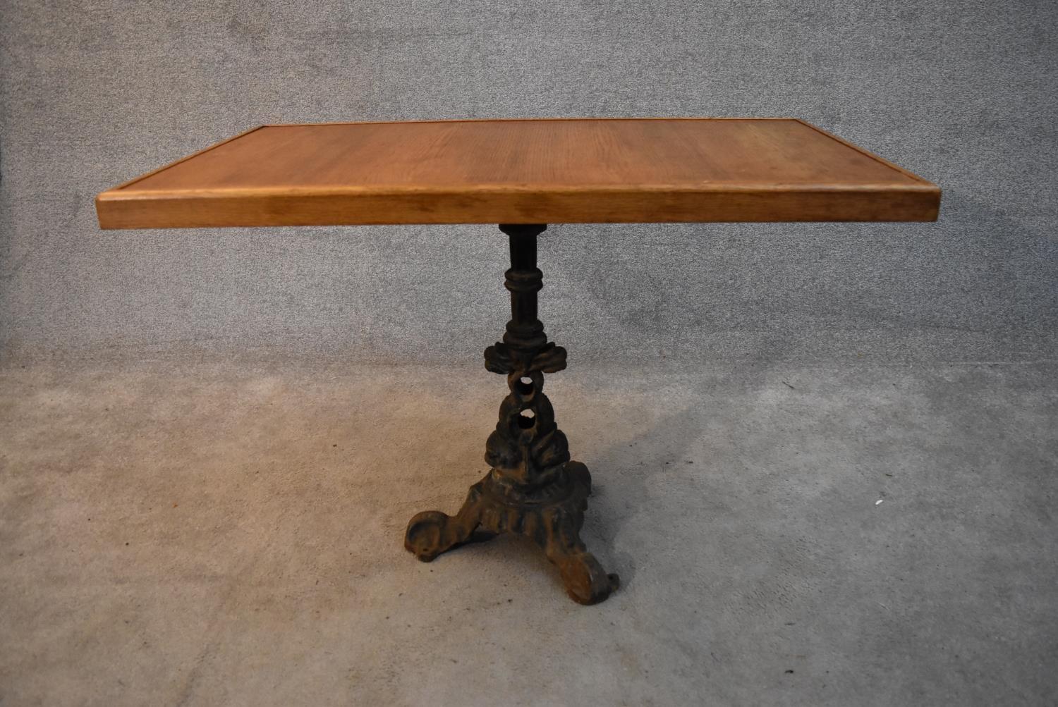 An oak topped conservatory table with cast iron pedestal base formed of entwined dolphins. H.