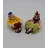Two antique hand painted porcelain lying figures, one male clown and a female clown, used as dishes.