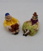 Two antique hand painted porcelain lying figures, one male clown and a female clown, used as dishes.