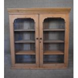 A 19th century pine bookcase section with arched glazed panel doors enclosing shelves. H.