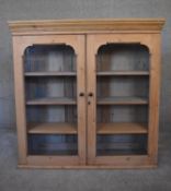 A 19th century pine bookcase section with arched glazed panel doors enclosing shelves. H.