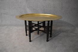 An Eastern brass topped table on folding hardwood stand. H.45xDia.90cm