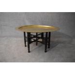 An Eastern brass topped table on folding hardwood stand. H.45xDia.90cm