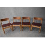 A set of four mid 20th century teak dining chairs in faux grained leather burgundy upholstery H.