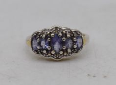 A silver and tanzanite and white stone five stone cocktail ring. Set with five oval mixed cut