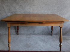 A Continental teak extending dining table on turned supports. H.74 W.224 D.91cm (fully extended).