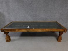 An antique Indian hardwood carved door converted to low coffee table with glazed top raised on