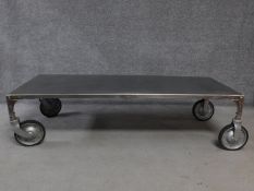 An industrial style aluminium coffee table on large trolley wheels. H.41 W.158 D.62cm