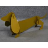 A metal painted sculpture of a sausage dog with a collar to its neck by British artist Peter