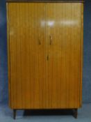 A 1960's vintage satin birch fitted wardrobe with asymmetric mahogany strung detail on tapering
