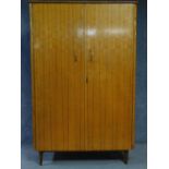 A 1960's vintage satin birch fitted wardrobe with asymmetric mahogany strung detail on tapering