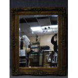 A gilt framed rococo style wall mirror with bevelled plate. 158x128cm