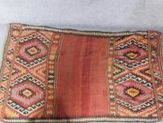 A Kilim style rug with repeating geometric designs on a terracotta field, fringed 255x140cm