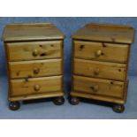A pair of contemporary pine bedside chests with three drawers on casters, by English maker Victoria.