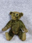 A 20th century green plush straw filled humpback teddy bear with jointed limbs.. H32cm.